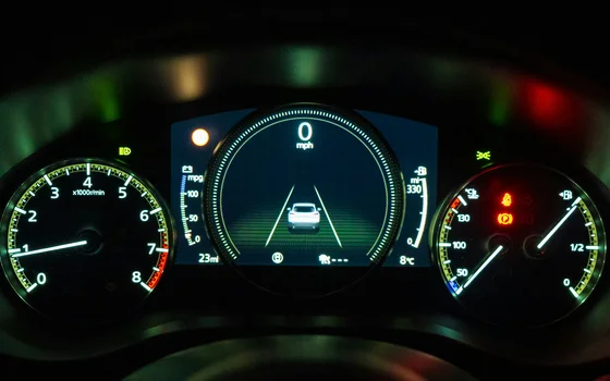 schwarz-weiss-kombiinstrument Beleuchtetes Armaturenbrett eines Autos bei Nacht. In der Mitte zeigt ein digitales Display 0 mph und eine Spurhaltegrafik. Links ist ein Drehzahlmesser und rechts Analoganzeigen für Kraftstoff und Motortemperatur zu sehen.