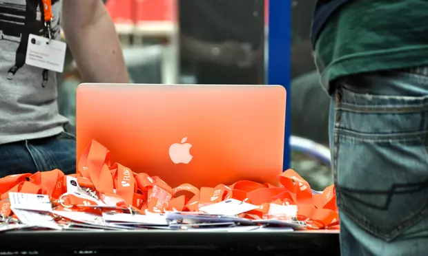 Nahaufnahme eines Notebooks auf einem Barcamp mit orangefarbenen Namensschildern im Vordergrund